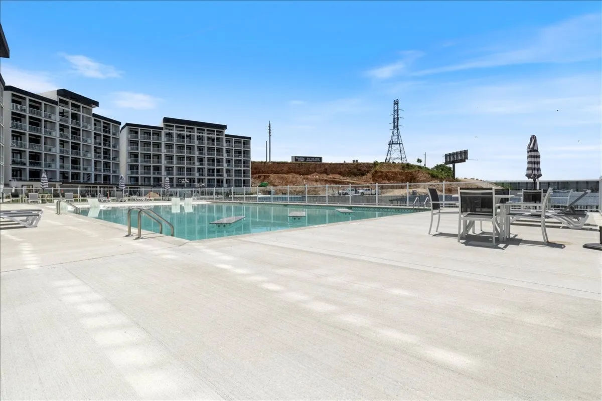 A refreshing pool area with sun loungers arranged for relaxation, framed by the surrounding buildings. The space exudes a laid-back atmosphere great for daytime socializing or evening poolside parties, capturing the lively side of group getaways.