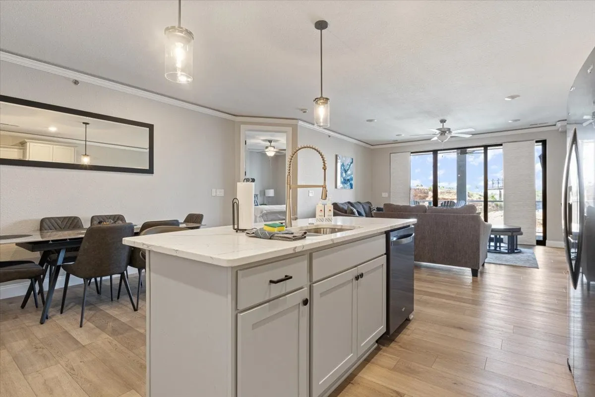 This inviting interior showcases an open-concept space that ties together the kitchen, dining area, and living room. Large windows offer abundant natural light and a glimpse outdoors, while the layout suggests both comfort and functionality for group gatherings or solo relaxation.