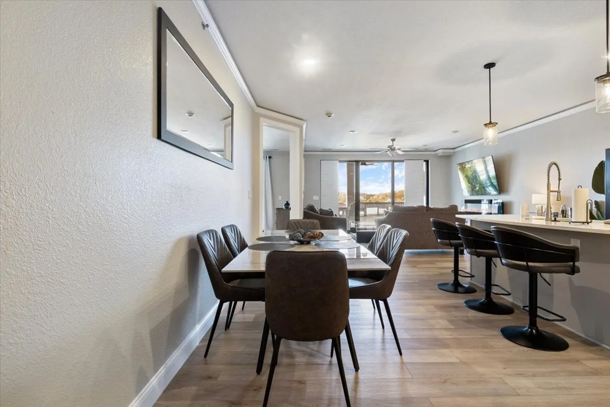 A stylish dining area featuring a contemporary table with bar stools, a cozy couch, and a television. The open-plan design encourages shared meals and lively socializing, while the overall decor feels modern and welcoming.